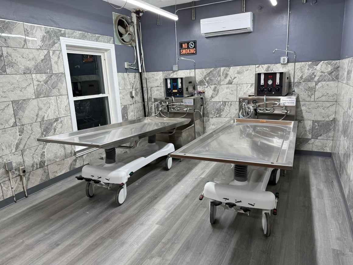 A side-by-side view of a hydraulic embalming table and a folded dressing table, emphasizing space-saving design