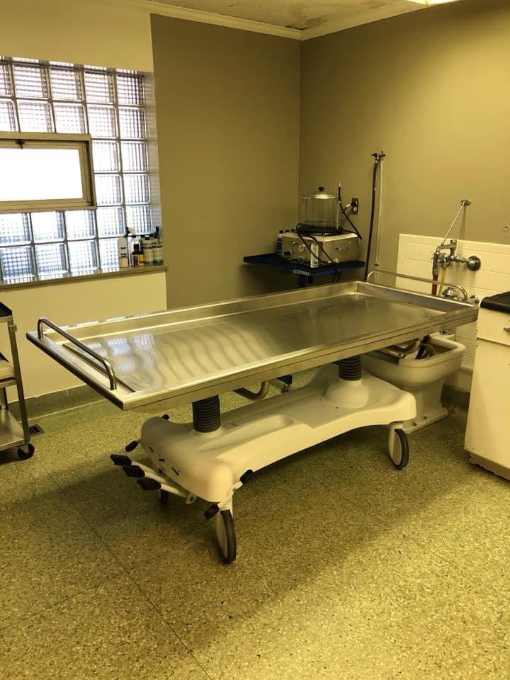 A side-by-side view of a hydraulic embalming table and a folded dressing table, emphasizing space-saving design